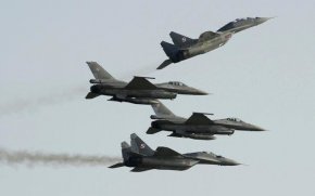 Два изтребителя Миг 29 руско производство на полските ВВС прелитат над и под два изтребителя F-16 американско производство на полските ВВС по време на авиошоуто в Радом, Полша, на 27 август 2011 г. 