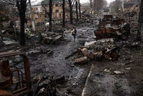 Жена се разхожда сред разрушени руски танкове в Буча, в покрайнините на Киев, Украйна, в неделя, 3 април. (Rodrigo Abd/AP)