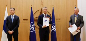 Посланикът на Финландия в НАТО Клаус Корхонен (вляво), генералният секретар на НАТО Йенс Столтенберг (в средата) и посланикът на Швеция в НАТО Аксел Вернхоф (вдясно) присъстват на церемония по повод кандидатурата на Швеция и Финландия за членство в НАТО в Брюксел, Белгия, на 18 май. (Йохана Герон/Reuters)